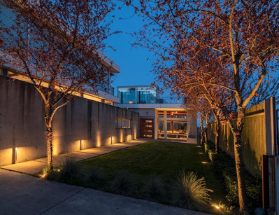 Warm architectural and landscape lighting illuminates mature trees, concrete walls, and garden pathways in the courtyard of a contemporary tri-level home in Seattle's Capitol Hill neighborhood. Outdoor lighting designed and installed by Northwest Outdoor Lighting. Photography copyright © Northwest Outdoor Lighting. All rights reserved.