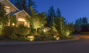 Front landscaping and pathway of a Tuscany community residence illuminated with subtle 3000K outdoor lighting.