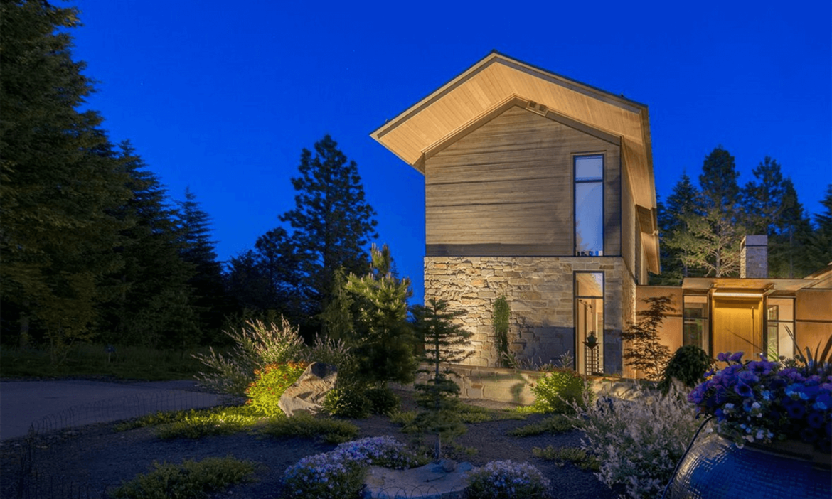 Warm architectural and landscape lighting highlights a contemporary stone-clad residence, ornamental grasses, and natural boulders at an Olson Kundig-designed home in Suncadia. Outdoor lighting designed and installed by Northwest Outdoor Lighting. Photography copyright © Northwest Outdoor Lighting. All rights reserved.