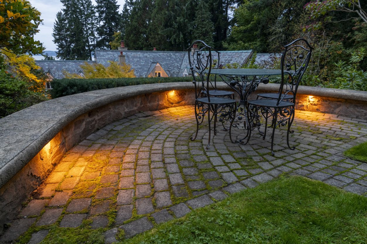Curved cobblestone seating area with integrated hardscape lighting highlighting stone textures and outdoor entertaining space.