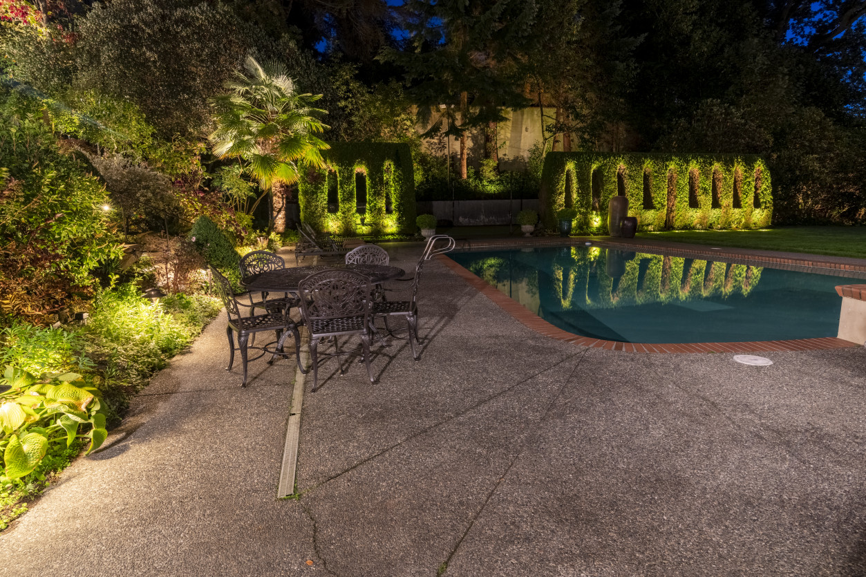 Outdoor patio and seating area lighting with illuminated stone surfaces and landscape accents creating a welcoming evening setting.