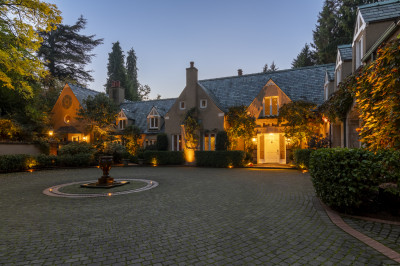 Front elevation architectural lighting of The Highlands Estate showcasing illuminated cobblestone motor court and fountain at entry.
