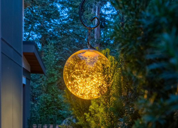 Custom NWOL manufactured “The Globe” outdoor fixture suspended among garden greenery, illuminated with Sunset Tone lighting at a Mercer Island Contemporary Estate.