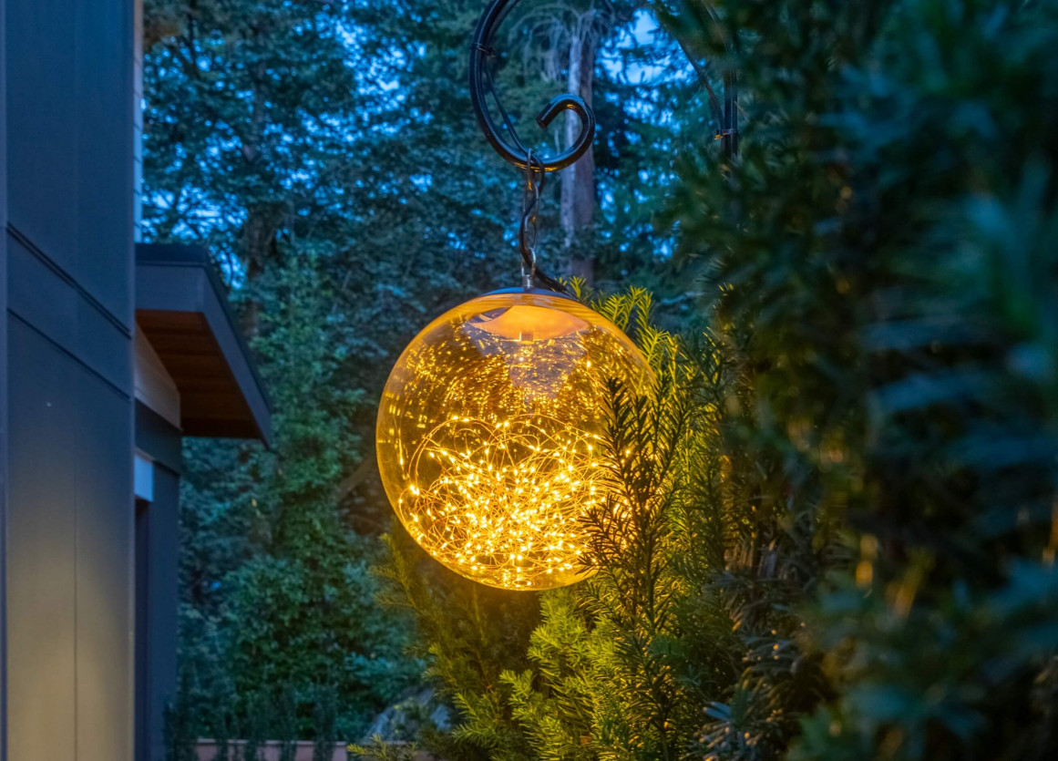 Custom NWOL manufactured “The Globe” outdoor fixture suspended among garden greenery, illuminated with Sunset Tone lighting at a Mercer Island Contemporary Estate.