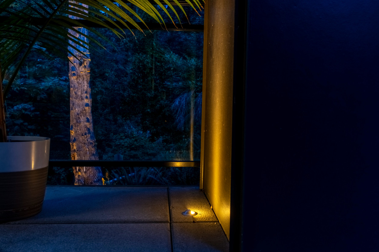Sunset Tone uplighting on architectural column and landscape plantings along covered patio and walkway at a modern Mercer Island home.