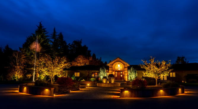 Dramatic front drive and entry courtyard in Auburn, Washington illuminated with Sunset Tone lighting to create a welcoming nighttime arrival.