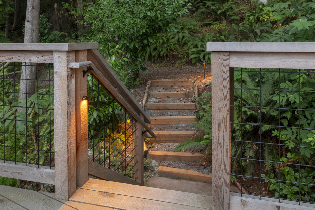 Sunset Tone step lighting illuminating wooden stairs surrounded by dense garden foliage at a Wind & Tide hillside estate in Edmonds, WA.