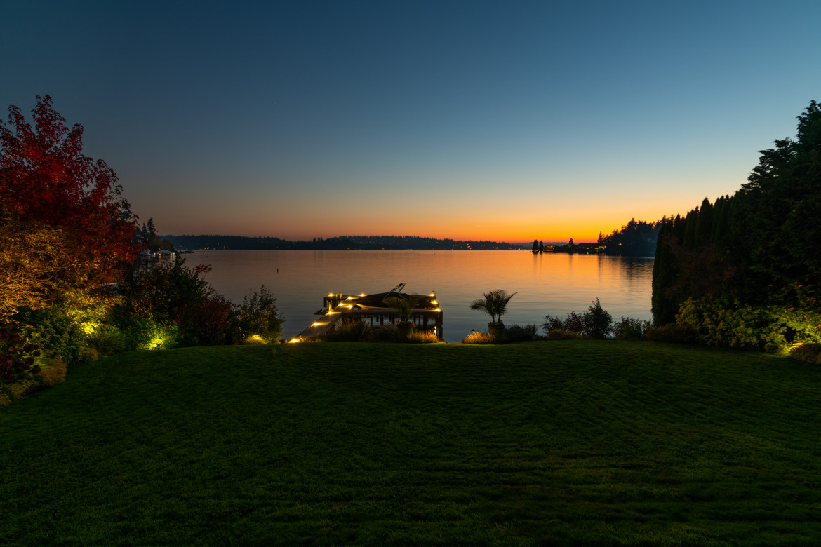Waterfront outdoor lighting on a Meydenbauer Bay home with illuminated dock and landscape at sunset in Bellevue, WA