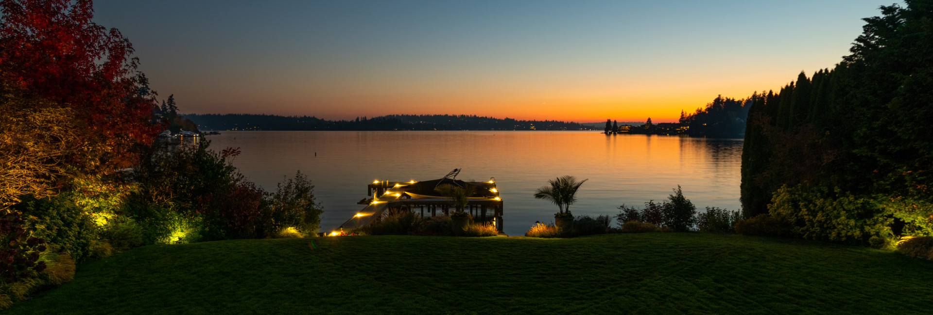 Waterfront outdoor lighting on a Meydenbauer Bay home with illuminated dock and landscape at sunset in Bellevue, WA