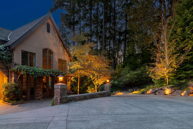 Warm 2700K uplighting on ornamental trees highlighting garden structure along the estate’s vehicle approach road.