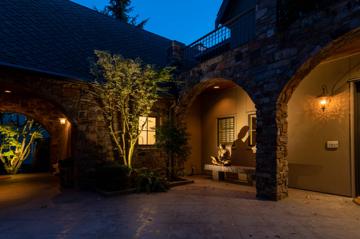Architectural and garden lighting emphasizing stone archway and front courtyard entry at Sammamish estate.