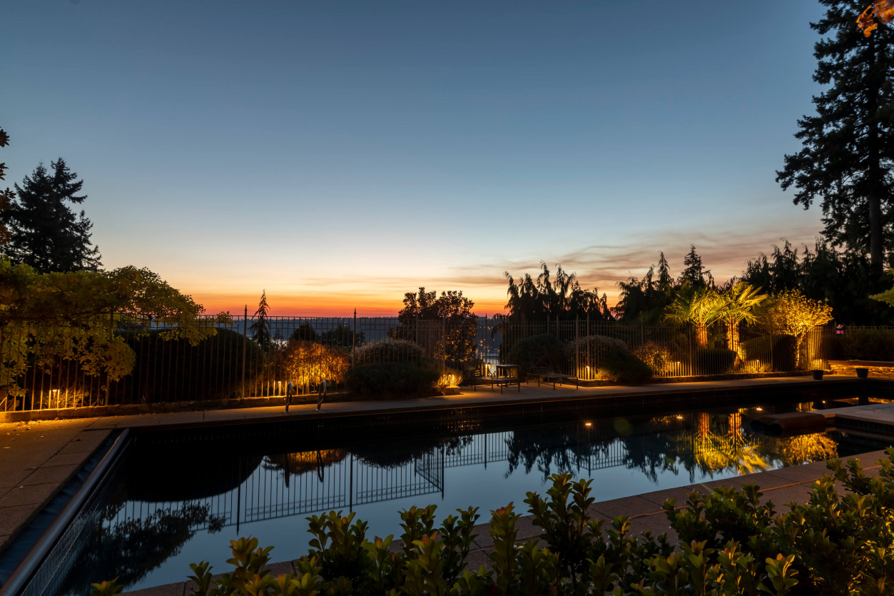 Poolside sunset reflecting warm architectural lighting and landscape uplights at a Sammamish estate designed by Northwest Outdoor Lighting.