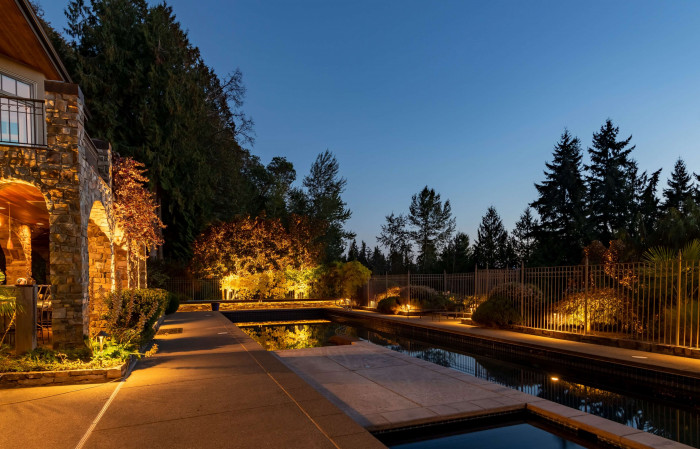Outdoor lighting around stone patio, hot tub, and architectural details with layered 2700K color temperature at a Sammamish custom estate.