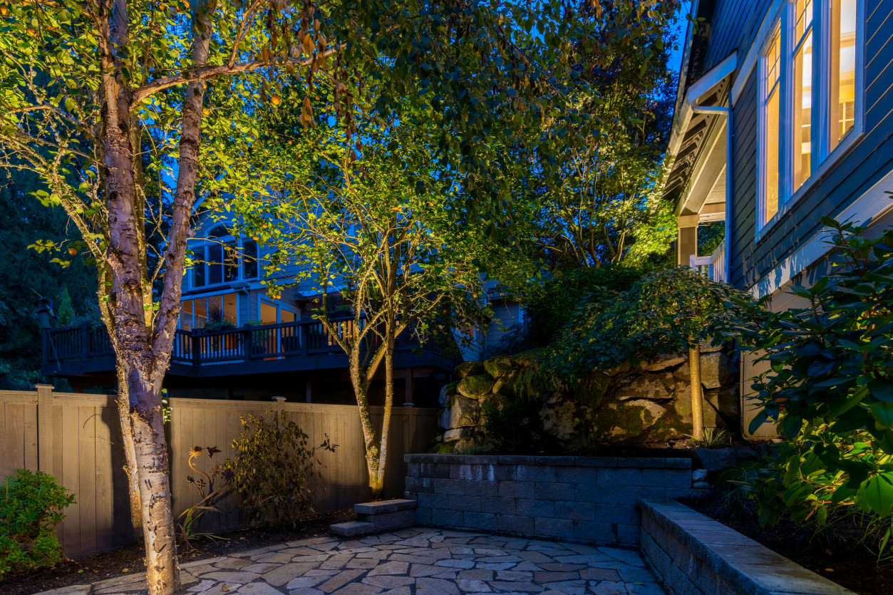 Evening lighting on a multi-level deck walkway surrounded by lush greenery at Sammamish family home.