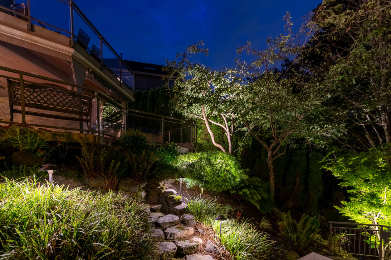 Stone pathway and terraced landscaping in Sammamish backyard lit with soft 2700K lighting, enhancing texture and garden structure.
