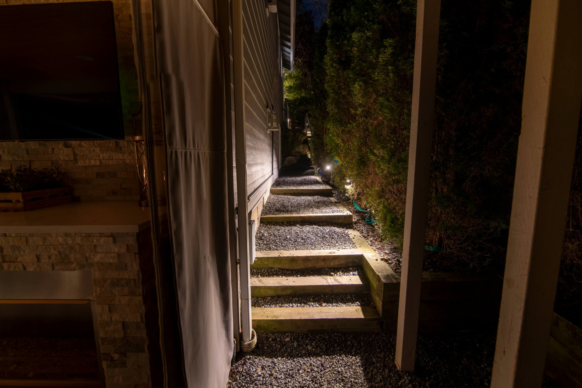 Side-yard pathway lighting with low-glare fixtures illuminating gravel walkway and wooden fencing in Sammamish — Northwest Outdoor Lighting 2700K.