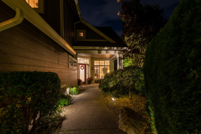 Warm architectural lighting at Sammamish home entry walkway highlighting hedges and façade — Northwest Outdoor Lighting 2700K.