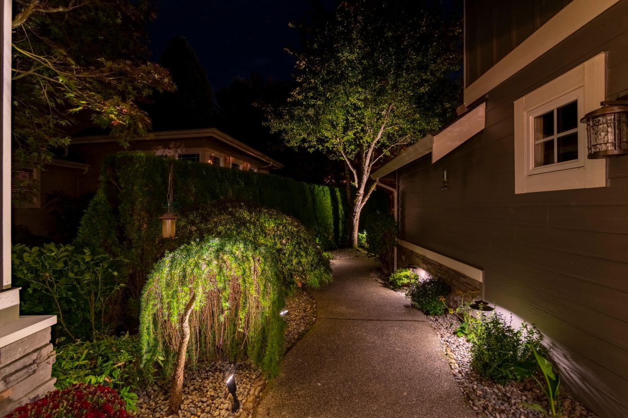 Evening walkway lighting guiding visitors along landscaped pathway toward backyard entertainment deck in Sammamish — Northwest Outdoor Lighting 2700K.