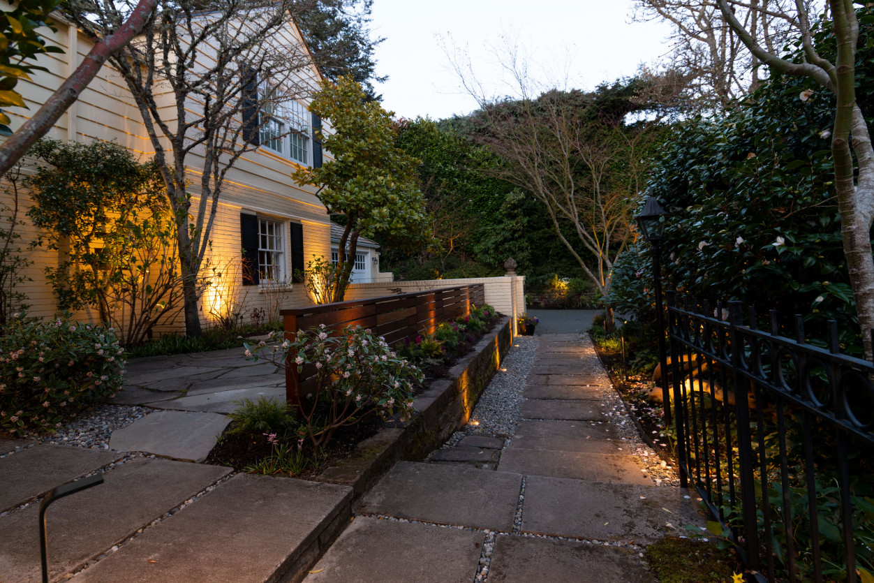 Stone pathway and garden landscaping lit with accent lighting at Magnolia Seattle residence.