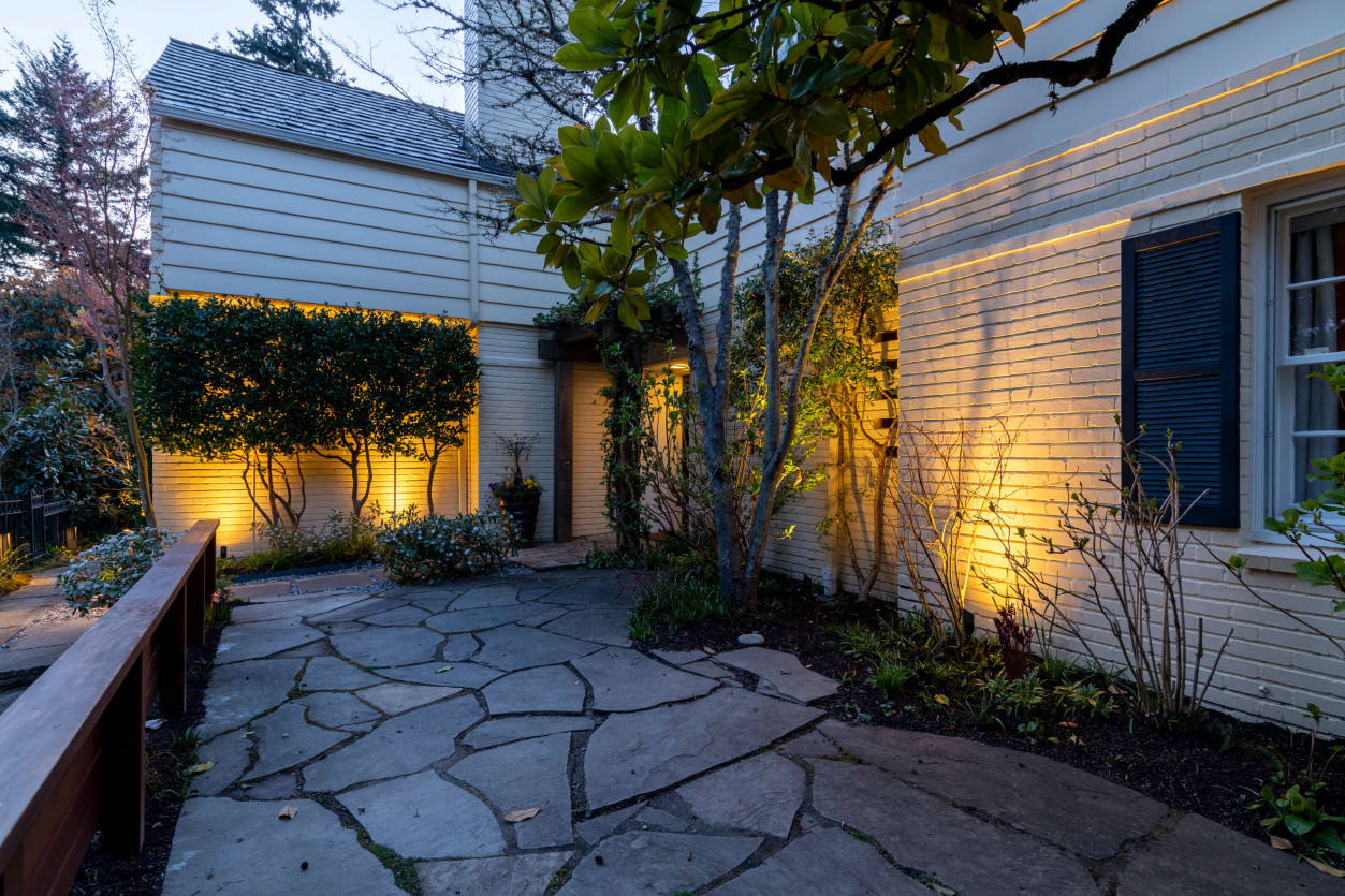 Warm architectural lighting along stone entry and modern siding at Magnolia Seattle home.