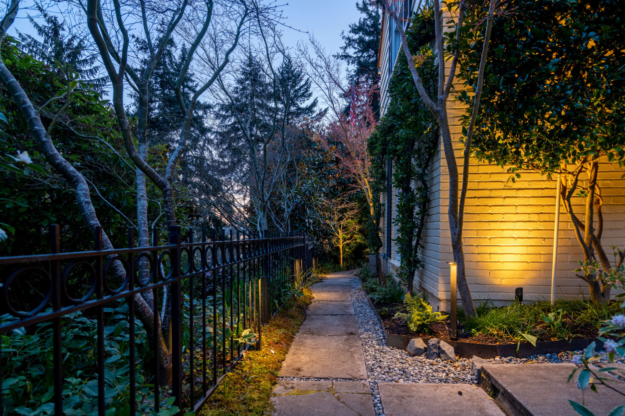 Illuminated pathway through dense landscaping near Seattle Magnolia property with warm outdoor lighting.