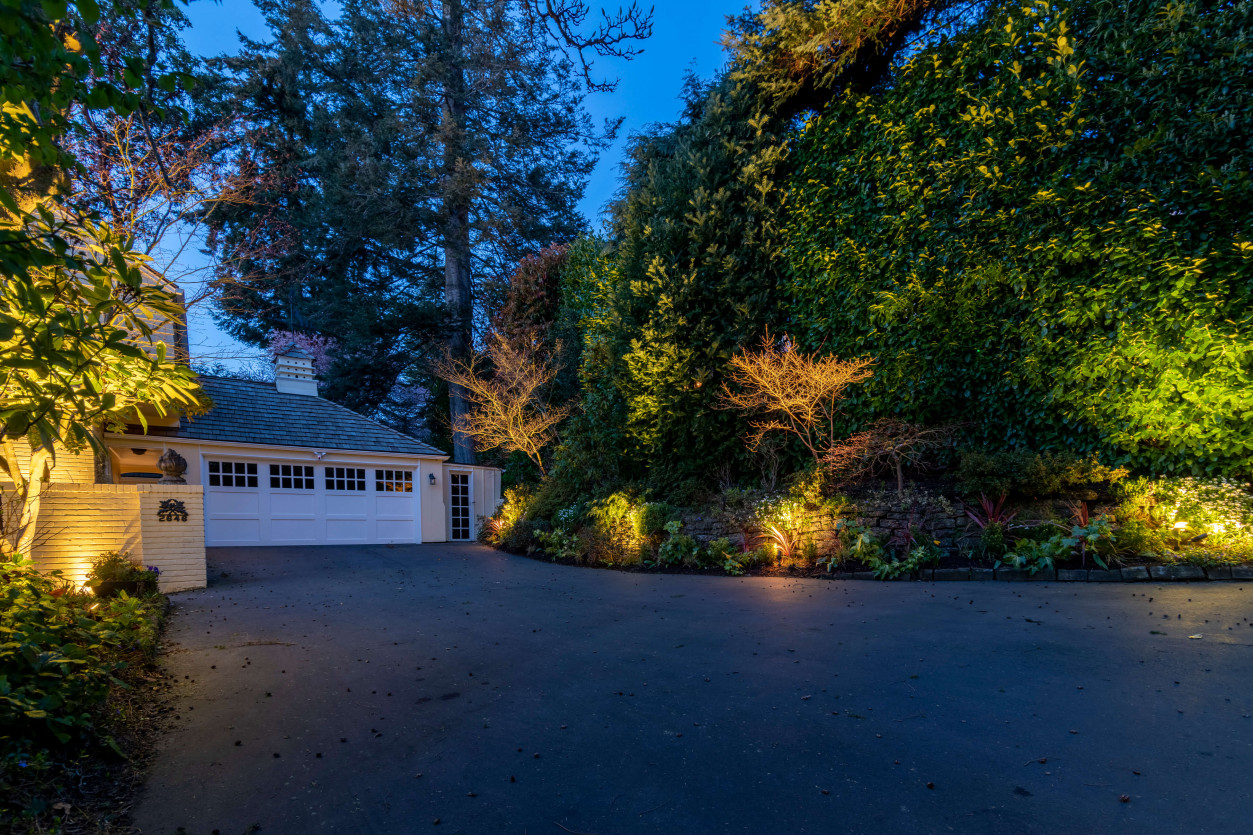 Driveway entry and landscaping lighting with warm LED lights guiding vehicle approach to Magnolia residence.