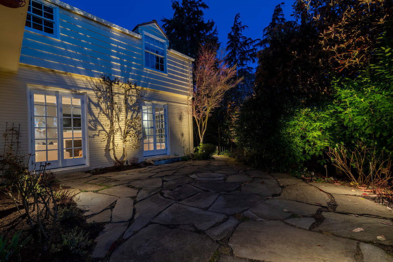 Architectural lighting on stone front porch and entry façade with surrounding landscape illumination.
