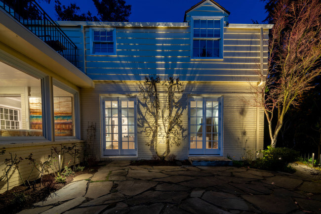 Backyard regrade and stone terrace lighting illuminating rear home elevation and mature tree canopy.