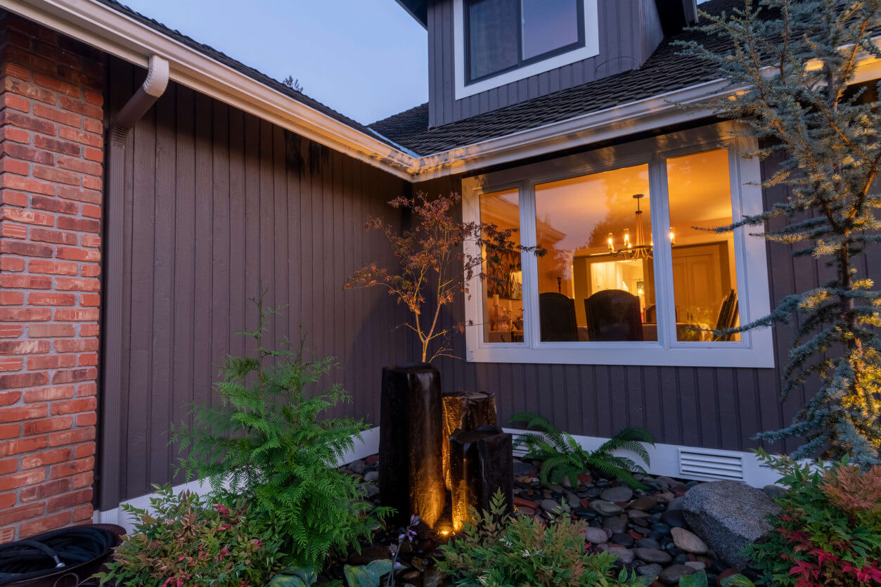 Front entry lighting highlighting stone fountain
 columns and planting bed